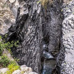 Close view of the rocks and the stream in the volcanic gorge of Gore Alcantara Botanical and Geological park, located 15 km from Giardini Naxos, Sicily, Italy