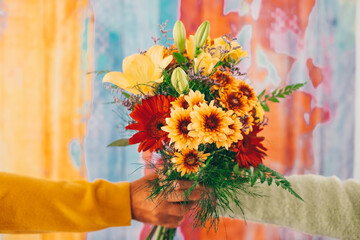 Valentine's Day Women's Day birthday holiday party. Close up cropped photo of female and male hands holding a bouquet of flowers isolated on colorful background.