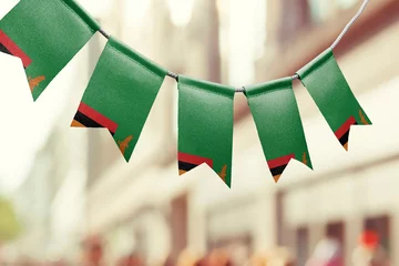 Foto op Aluminium A garland of Zambia national flags on an abstract blurred background © butenkow