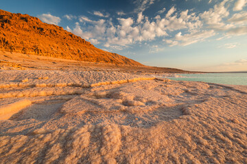 Fototapeta na wymiar Landscapes from the Dead Sea in the light of the golden hour - interesting salt formations make an amazing impression.