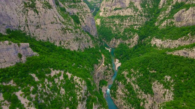 Aerial video of the stunning Moracha River canyon in Montenegro. Soar above the magnificent natural scenery, capturing stunning aerial views of the towering cliffs, crystal-clear river, and lush