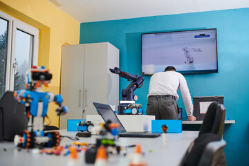 A student testing his new invention of a robotic arm in the laboratory, showcasing the culmination of his research and technological prowess.