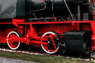 Naklejka premium Vintage steam train with vibrant red metal wheels.