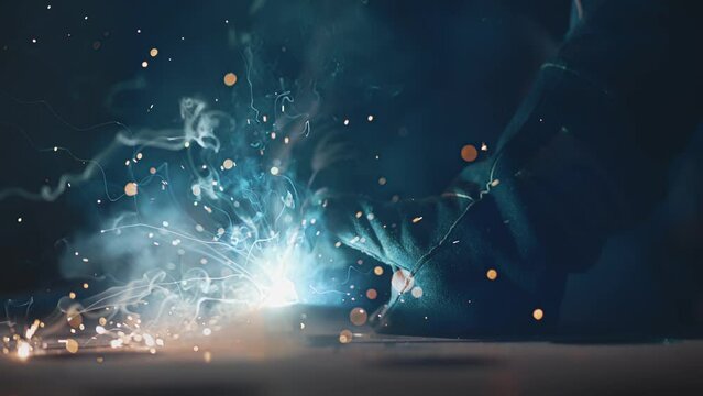 The man is welding. Welding with argon or electrode, using a welding machine. Sparks and flashes fly.
