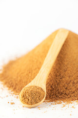 Brown unrefined cane sugar Panela in a wooden spoon on a white.