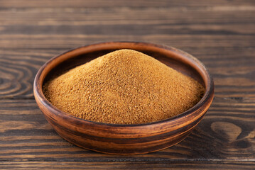 Unrefined cane brown sugar Panela in a clay bowl on a wooden table.