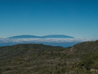 Fototapeta premium View on La Palma island seen from trail to Alto de Garajonay at Garajonay National Park. White clouds and blue sky above. La Gomera, Canary Islands, Spain, Europe.