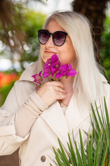 Portrait of middle-aged woman against background of green leaves. Success, antiaging 
