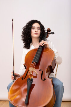 Woman playing violin cello while sitting on chair