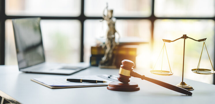 Law Firm Courtroom Law Books, Computer And Scales Of Justice On Table In Lawyer Office