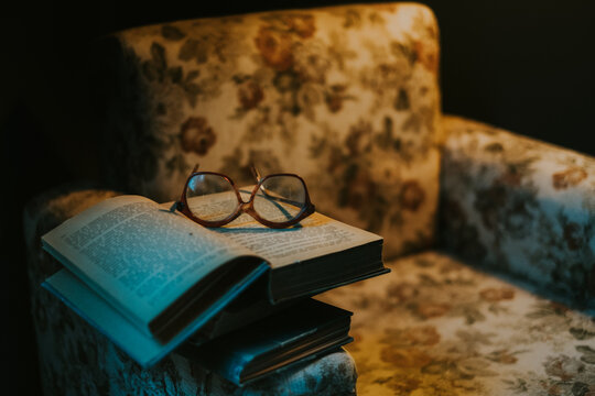 Eyeglasses and opened book on armchair