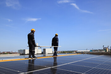 Men technicians carrying photovoltaic solar module on roof . Solar technician with safety PPE installing solar panel system . Concept of alternative and renewable energy.