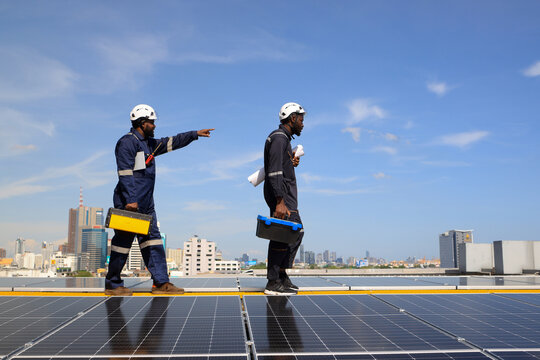 Electrical engineer team wearing safety PPE handle tool box walk on solar rooftop , Green Renewable energy for industry concept