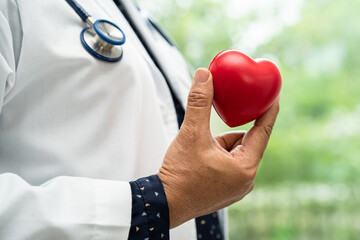 Doctor holding a red heart in hospital ward, healthy strong medical concept.