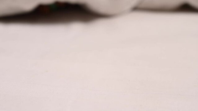 Woman taking mint vibrator lying under white blanket. 
