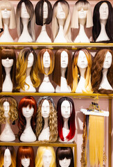 Multi-colored wigs are worn on the heads of mannequins.