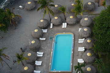 Pool and round palapas, at Beachside condo resort, Nueva Gorgona, Panama 2023