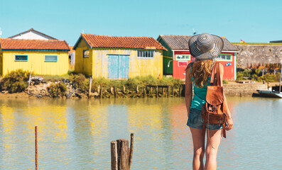 Woman travel in island Oleron- Charente Maritime,  canal with traditional fishing colored house - Tour tourism in France, Nouvelle aquitaine - obrazy, fototapety, plakaty