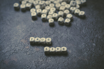 Las palabras vive de verdad escrita con cubos de madera sobre un fondo negro. Primer plano de elementos de madera