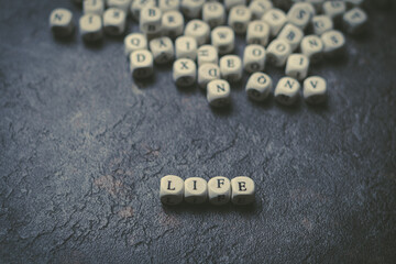 La palabra vida escrita con cubos de madera en primer plano sobre fondo negro. Foto conceptual con letras
