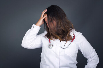 Shot of happy young woman with positive smile, has long hair, rejoices having weekend and good rest after hard working exhausting week, isolated on gray wall.