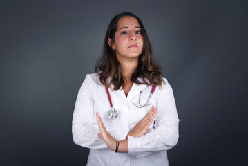 Young beautiful brunette girl wearing casual clothes standing over isolated background. Has rejection angry expression crossing hands doing refusal negative sign.