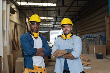 Portrait of two male carpenter working in wood workshop. Group of male joiner wearing safety...