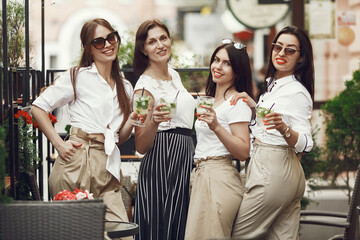 Four elegant adult women with beverages in a city