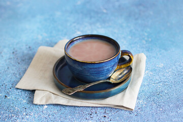 Cup of cappuccino for breakfast. Blue cup with latte on blue saucer on light blue background. Coffee time