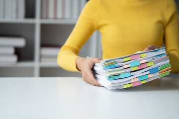 Close up view of young businesswoman working with stack of papers on the office room.
