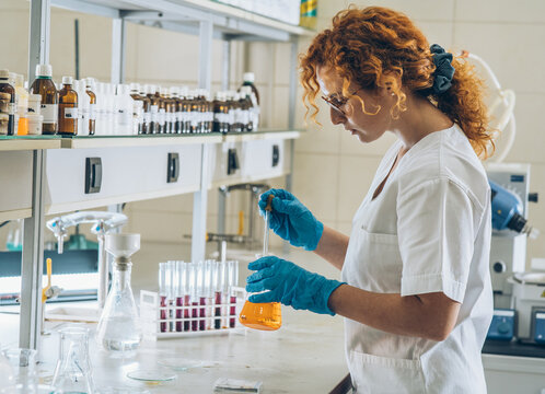 Red hair female chemistry scientist doing experiment in the lab.	
