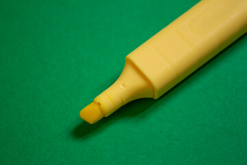 Yellow marker isolated on green background. Yellow felt-tip pen, closeup.
