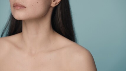 Perfect chin, slender neck and naked shoulders of a woman on a blue background close up. Skin care, body care, cosmetology, plastic surgery. - obrazy, fototapety, plakaty