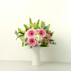 Bouquet of pink gerberas in a vase against a white wall