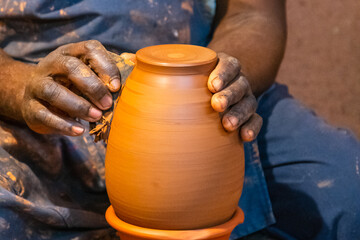 Gros plan sur les mains d'un homme qui fabrique une poterie en argile.	