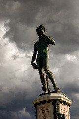 David statue on dramatic clouds background.