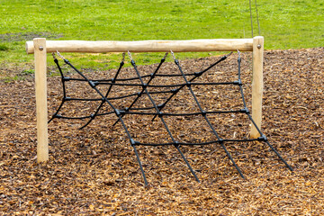 Wooden climbing frame with net in childrens outdoor playground.