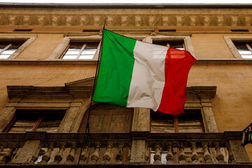 Italian flag on the old building balcony in the old town. Bottom view.
