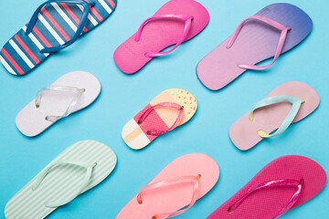 Many bright flip flops on color background, top view