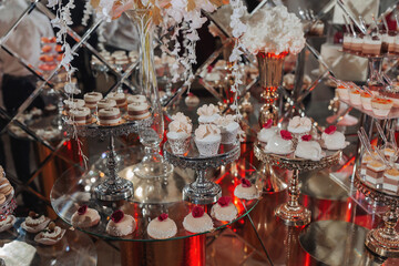 A delicious wedding. Candy bar for a banquet. Celebration concept. Fashionable desserts. A table with various sweets, candies. Fruits, cakes, macaroons, meringues