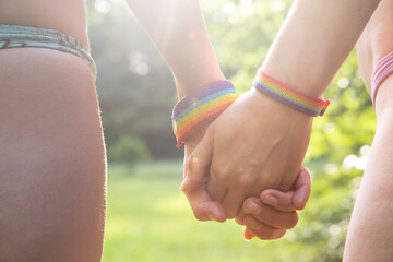 Bikini-Wearing Lesbian Couple Connected by Rainbow Bracelets in pride month. Lgtbq anb diversity.