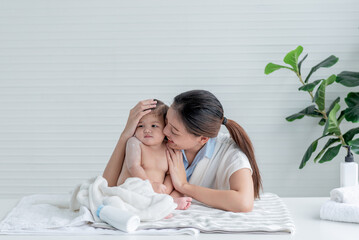 Asian mother attractive and young is applying talcum powder to her 7-month-old daughter after...