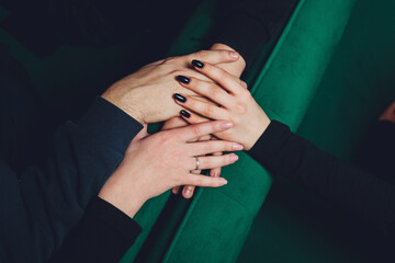 two man and three women holding hands on a table implying a polyamory relationship or love triangle.