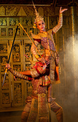 Fototapeta na wymiar Vertical image of Khon or traditional Thai classic masked from the Ramakien characters action of traditional dance with fighting between human and giant with Thai painting on the wall in background.
