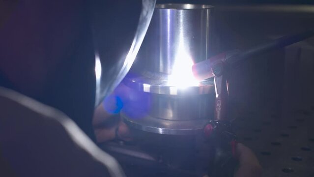 A welder makes a precision weld on a stainless-steel element. The element is used for professional kitchen equipment.