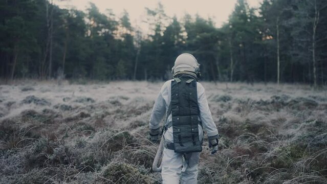 astronaut walks trough forest into forest clearing