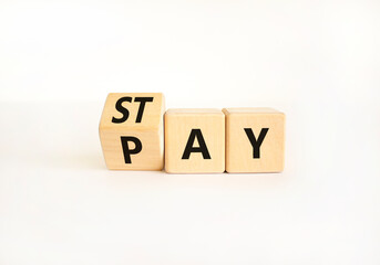 Stay and pay symbol. Businessman turns wooden cubes and changes the word Stay to Pay. Beautiful white table white background. Copy space. Business and stay and pay concept.