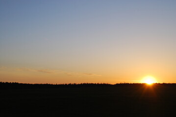Sunset over the dark horizon. Spring evening, the sky with rare clouds, the sky is dark blue with...