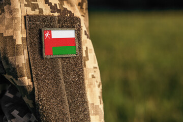 Close up millitary woman or man shoulder arm sleeve with Oman flag patch. Troops army, soldier camouflage uniform. Armed Forces, empty copy space for text

