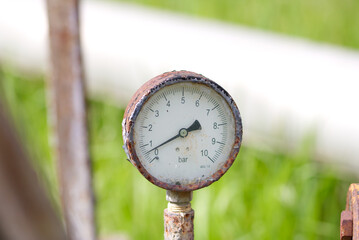 Close up of manometer measuring water pressure. Pipes and valves at industrial plant.